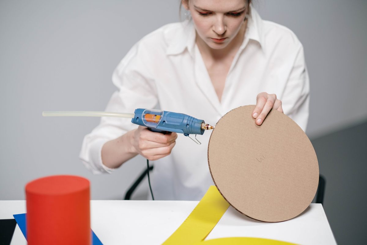 Application d'un cordon de colle thermofusible sur du carton fort — Photo : cottonbro studio / Pexels